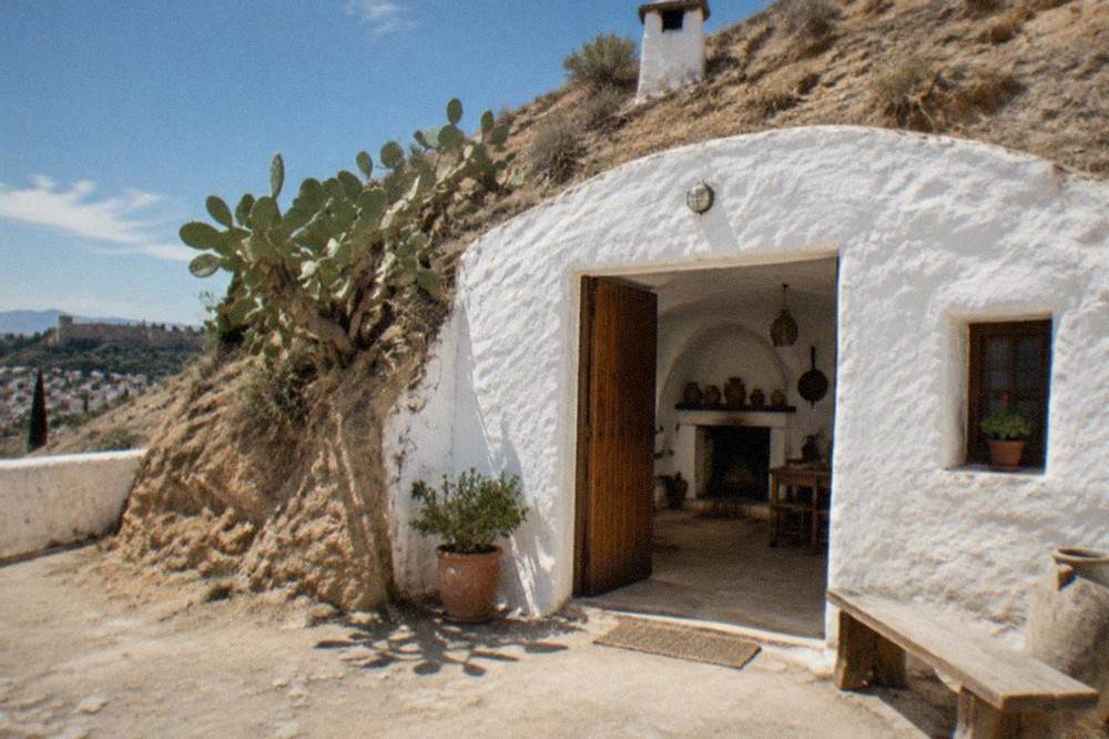 A cave interior with whitewashed walls, a hearth and traditional household objects on display