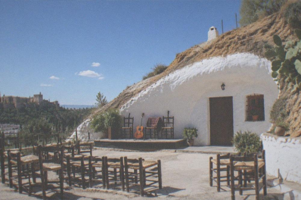 A cave performance space with low chairs arranged in front of a small raised corner for musicians