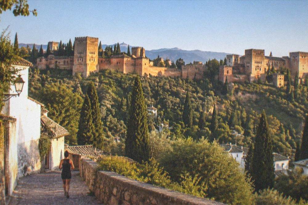 The Alhambra and its towers seen across a valley from the Sacromonte hillside at golden hour