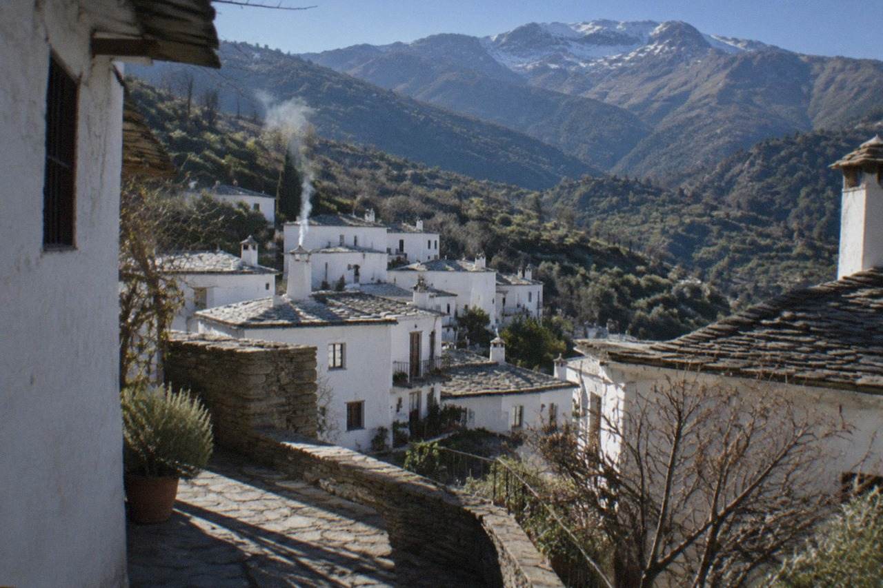 White mountain villages terraced into a green hillside under a clear sky