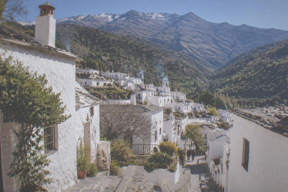 A stone village lane sloping between whitewashed houses in bright morning light