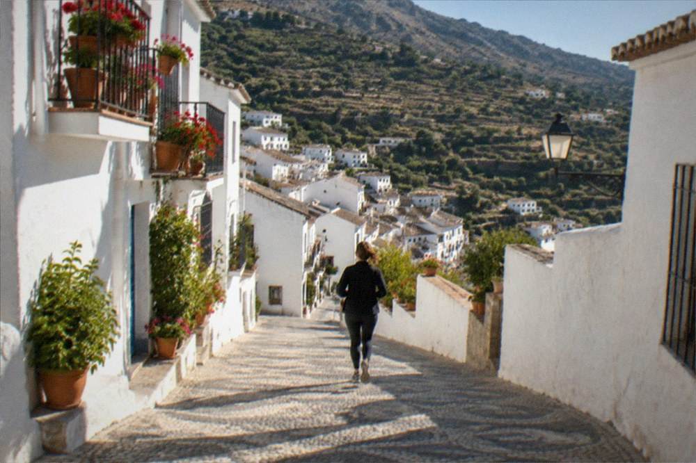 Terraced fields and dry-stone walls climbing a mountainside above a small white village