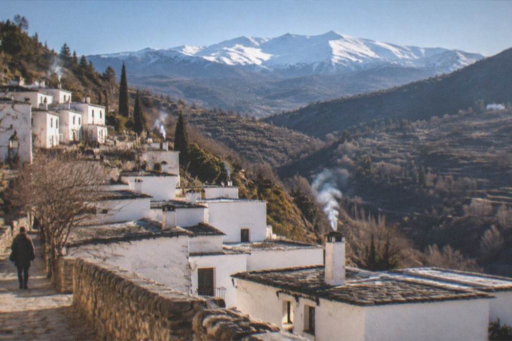 A wide view of terraced valleys and distant snow-capped peaks at golden hour