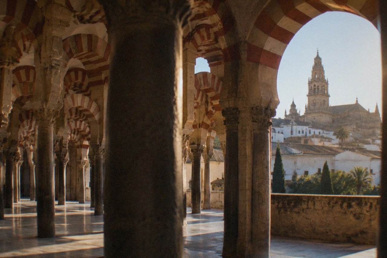 The historic skyline of Cordoba with its mosque-cathedral bell tower rising above rooftops in warm afternoon light