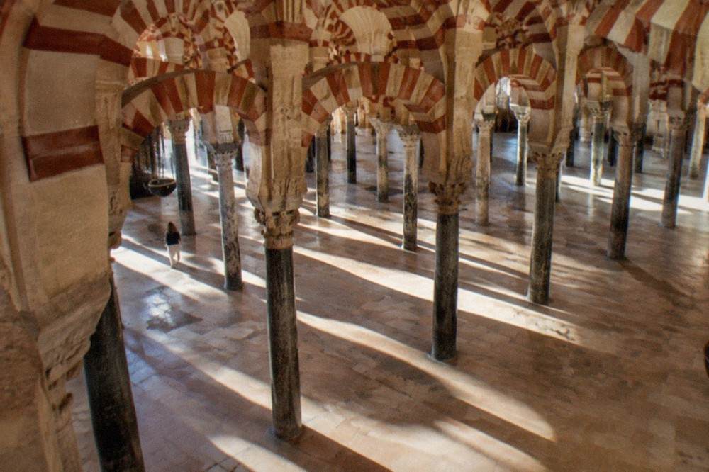 Rows of red and white striped arches and stone columns inside the mosque-cathedral of Cordoba