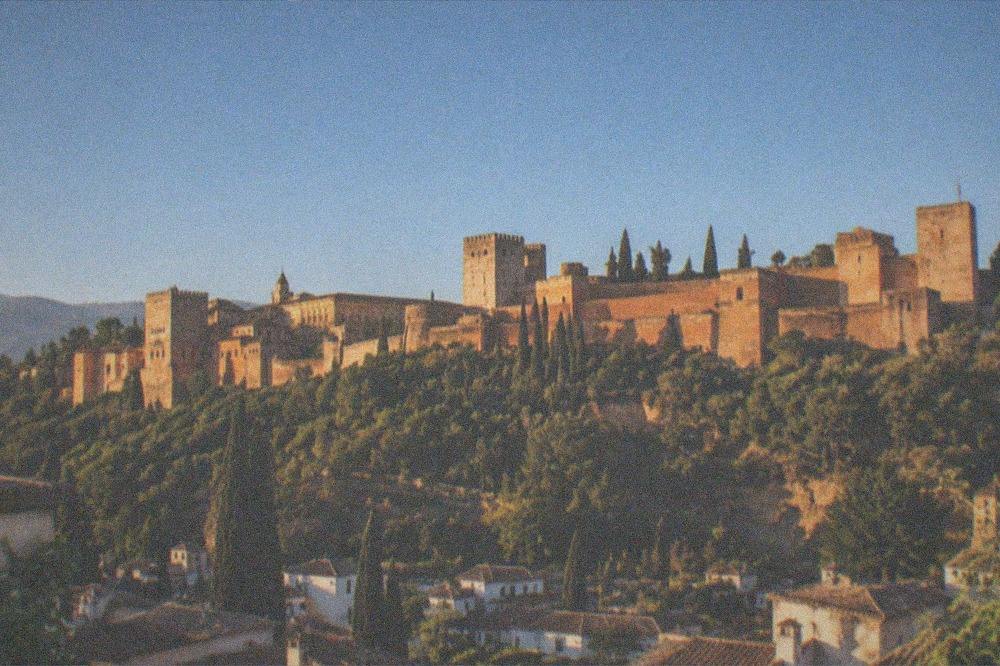 An evening view of the Alhambra glowing above the city from a hillside viewpoint in Granada