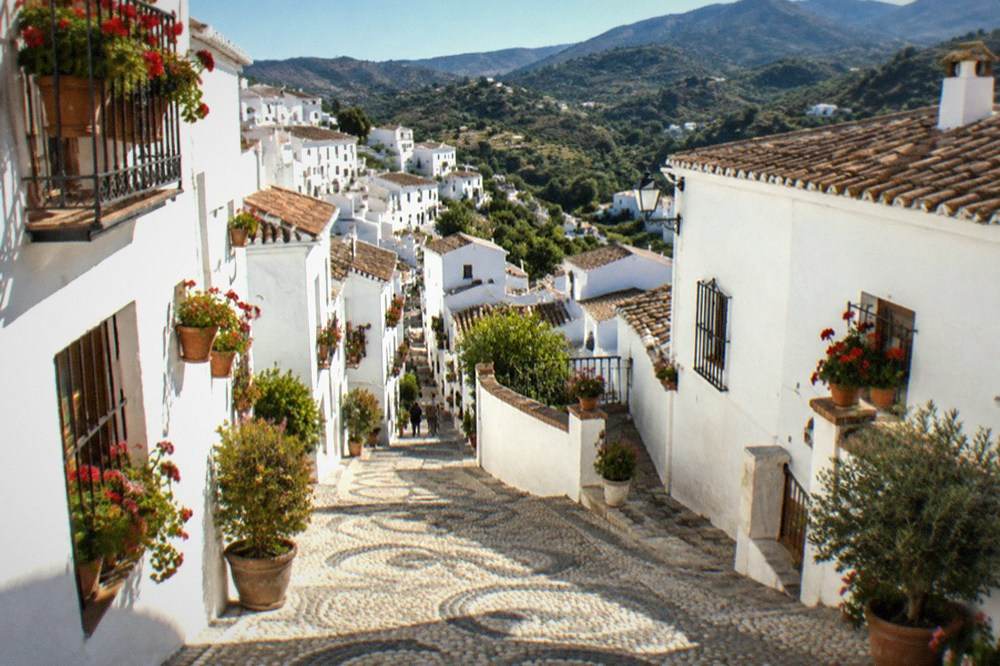 Flat-roofed white villages terraced into a green valley in the Alpujarras