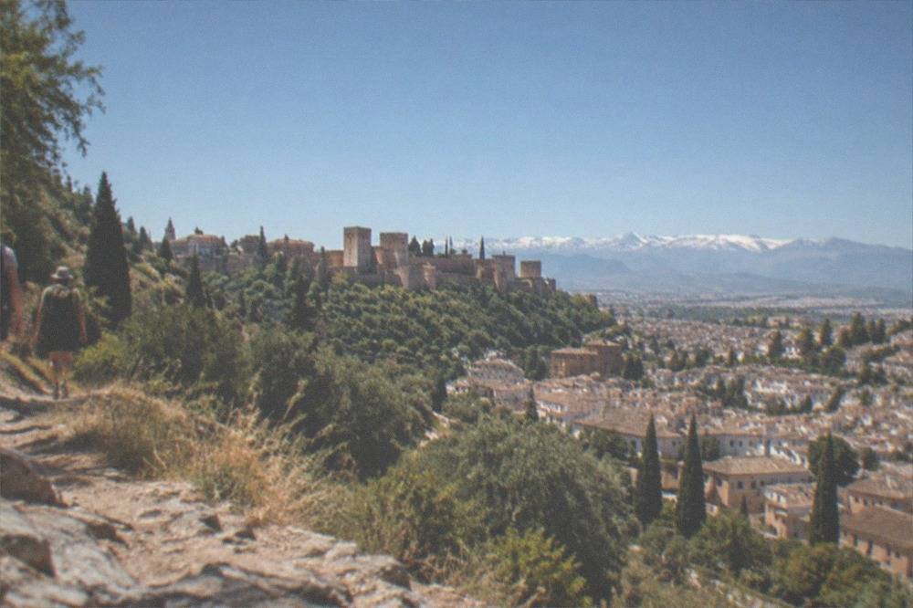 Hikers on a mountain trail above Granada with the city visible below