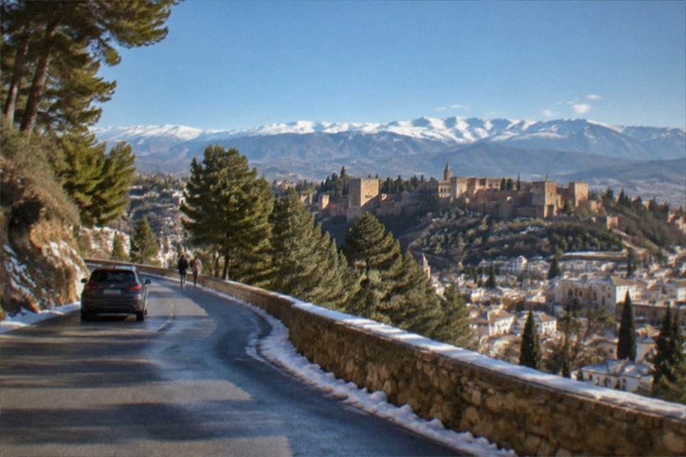 A mountain road winding through snow-dusted pine slopes above Granada