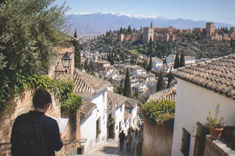 A traveller checking a map at a viewpoint above the Granada countryside
