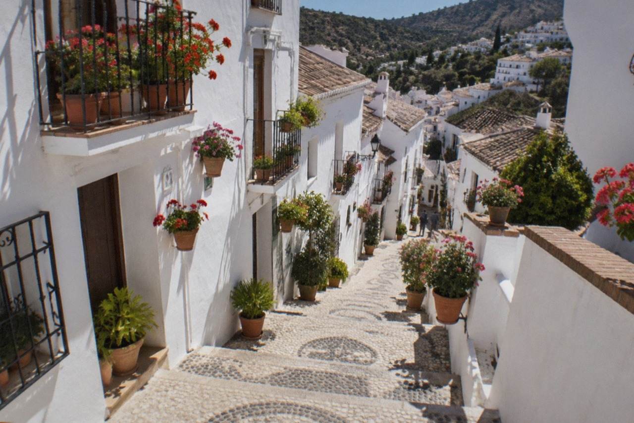 White-washed houses of a hillside Andalusian village with narrow stepped lanes and potted flowers