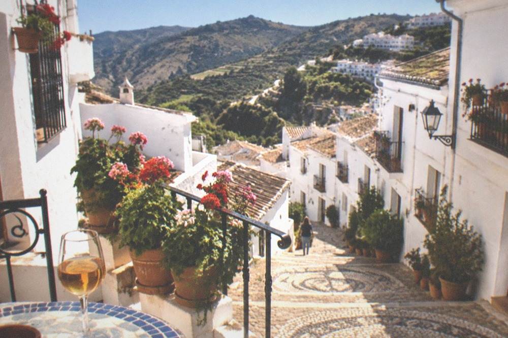 A terrace table with a glass of local sweet wine overlooking a valley