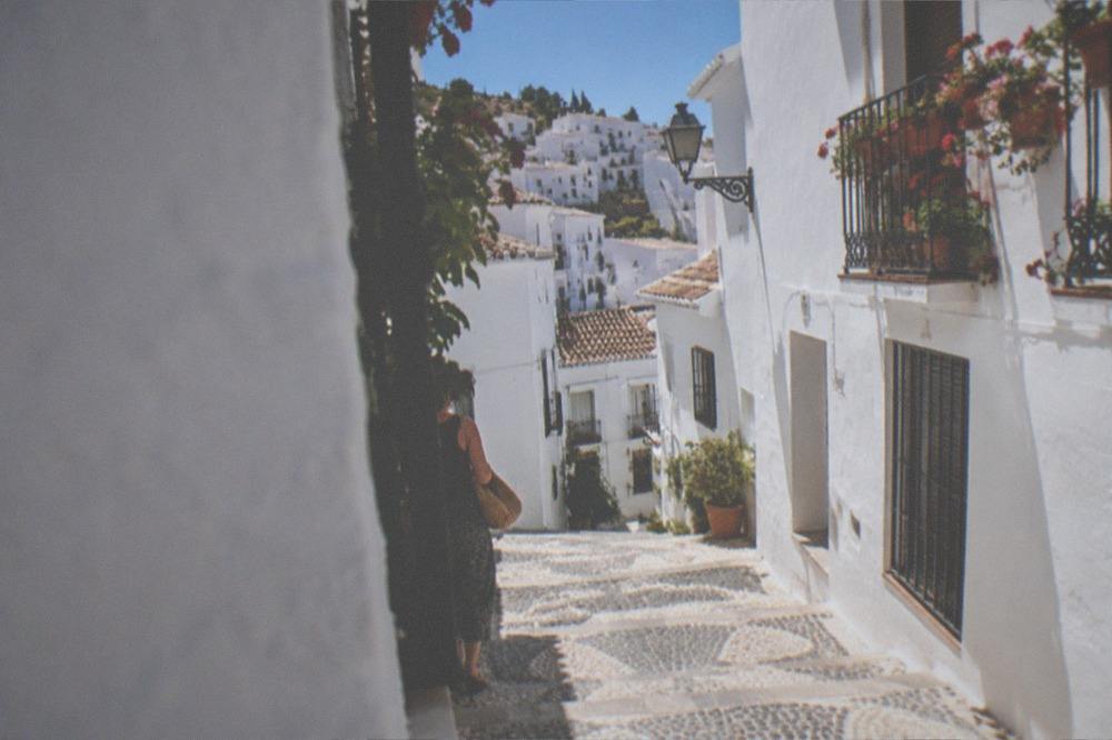 A stone staircase between white walls with bright sunlight and deep shadow
