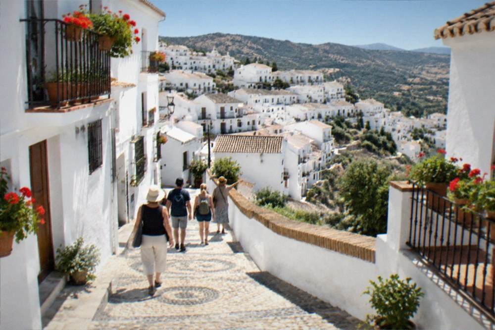 A small group of visitors walking with a guide along a whitewashed street