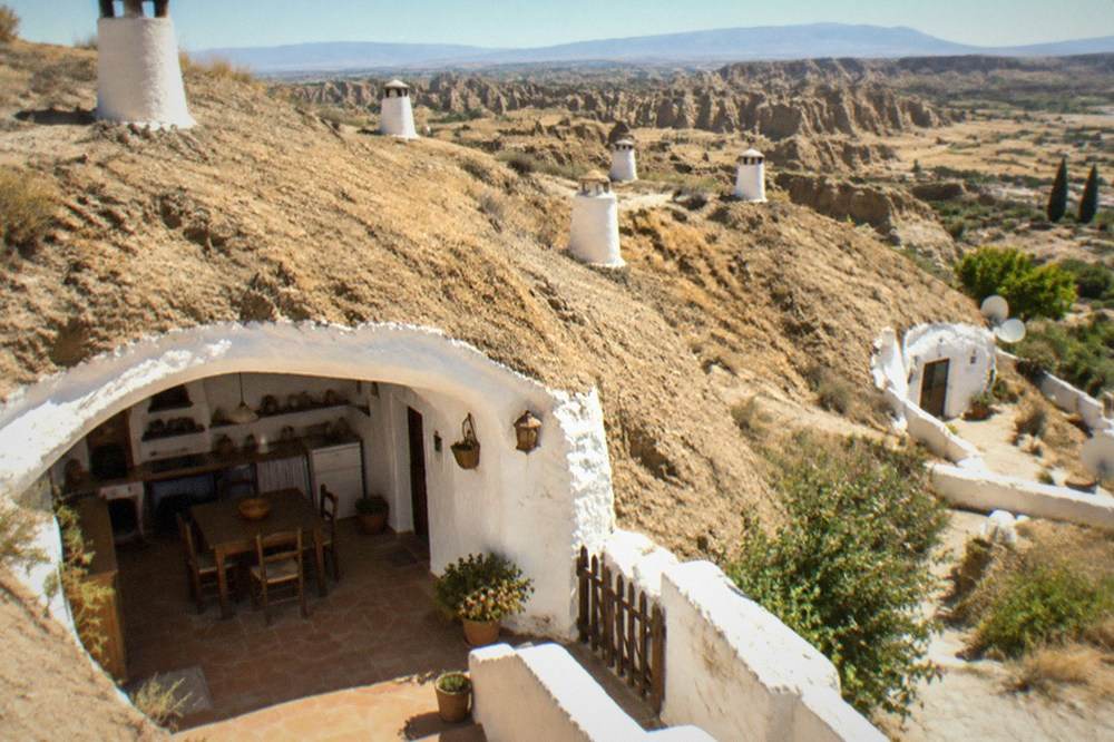 A furnished cave house interior with whitewashed arched walls and rustic kitchen equipment