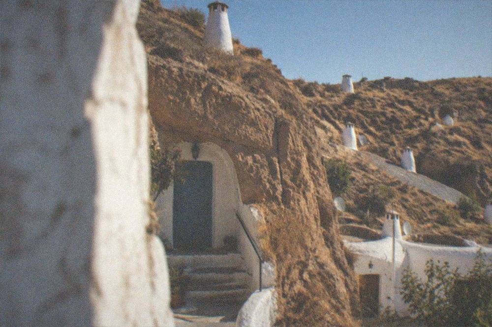 A cave dwelling entrance carved into a cliff face with a painted door and steps