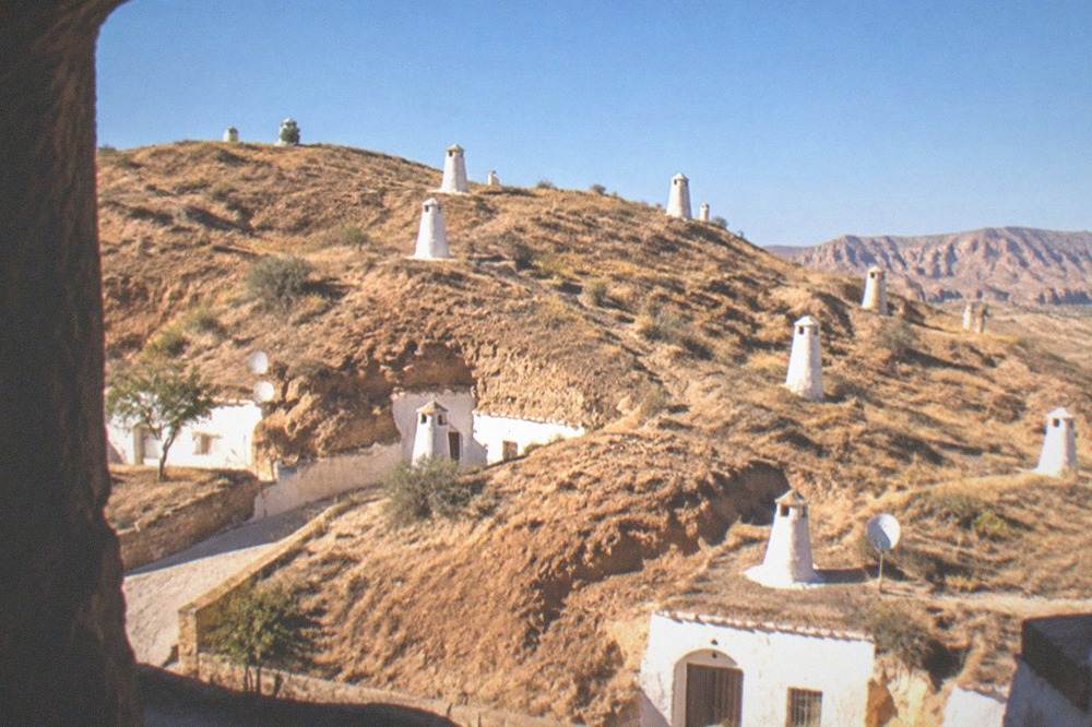 A hillside of cave house chimneys lit by warm late afternoon sun