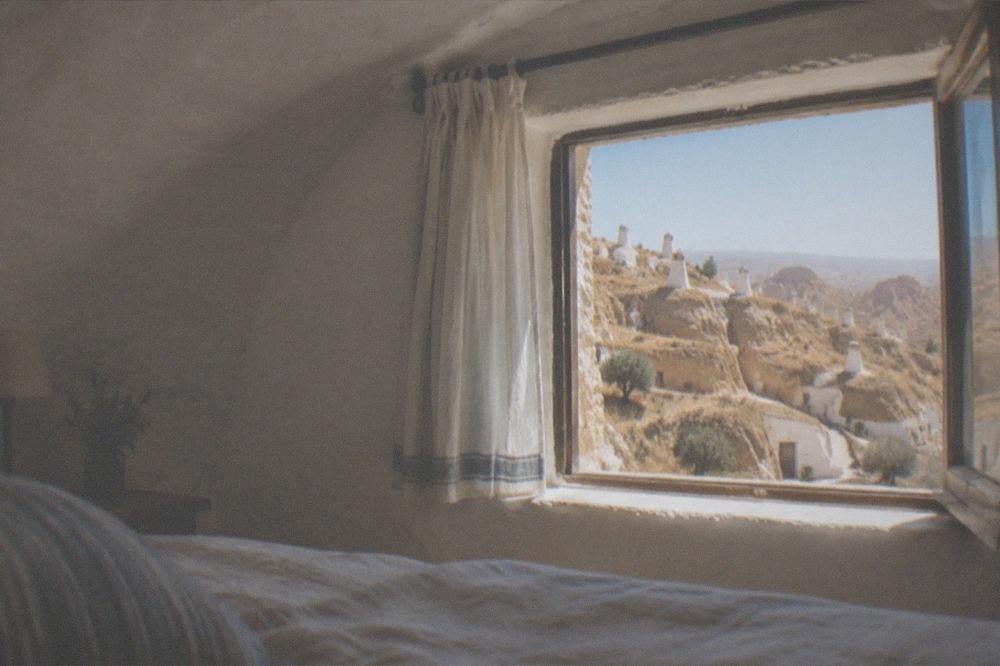 A cozy cave bedroom with arched whitewashed ceiling and a small window
