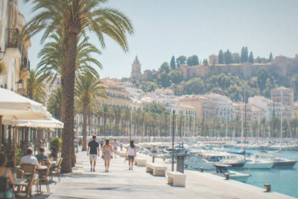 Narrow old-town street with cafe tables and historic facades in Malaga