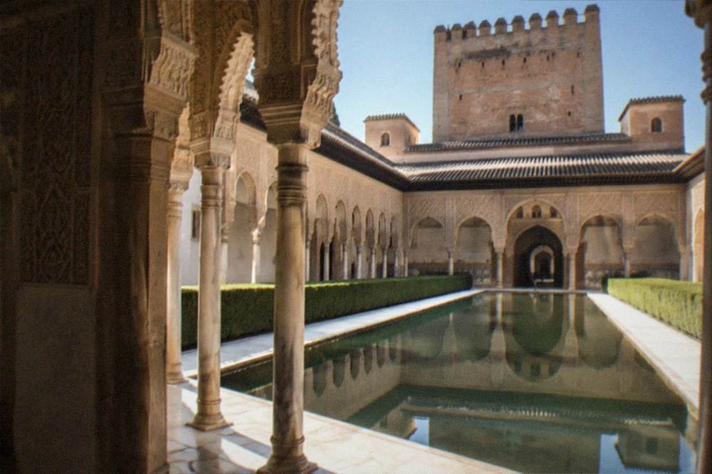 Ornate Moorish arches and carved stucco walls inside a Nasrid palace courtyard