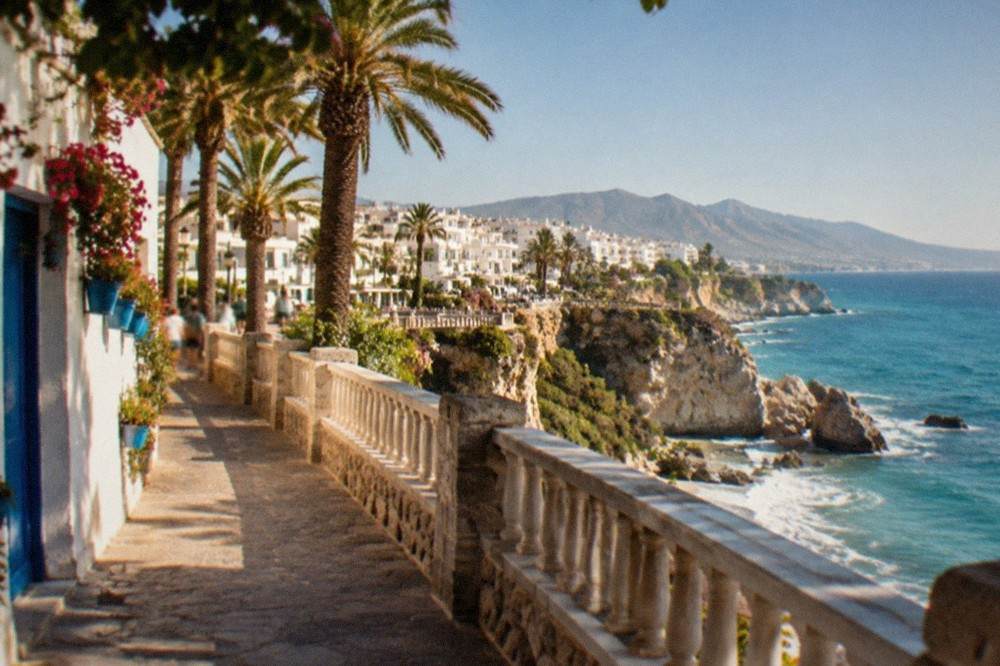 Narrow whitewashed street in a coastal Andalusian town with blue doors and flower pots