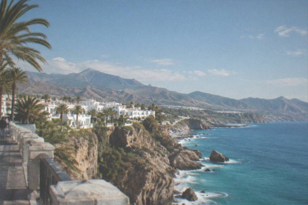 Mountain road winding down toward the sea with dry hills and distant coastline