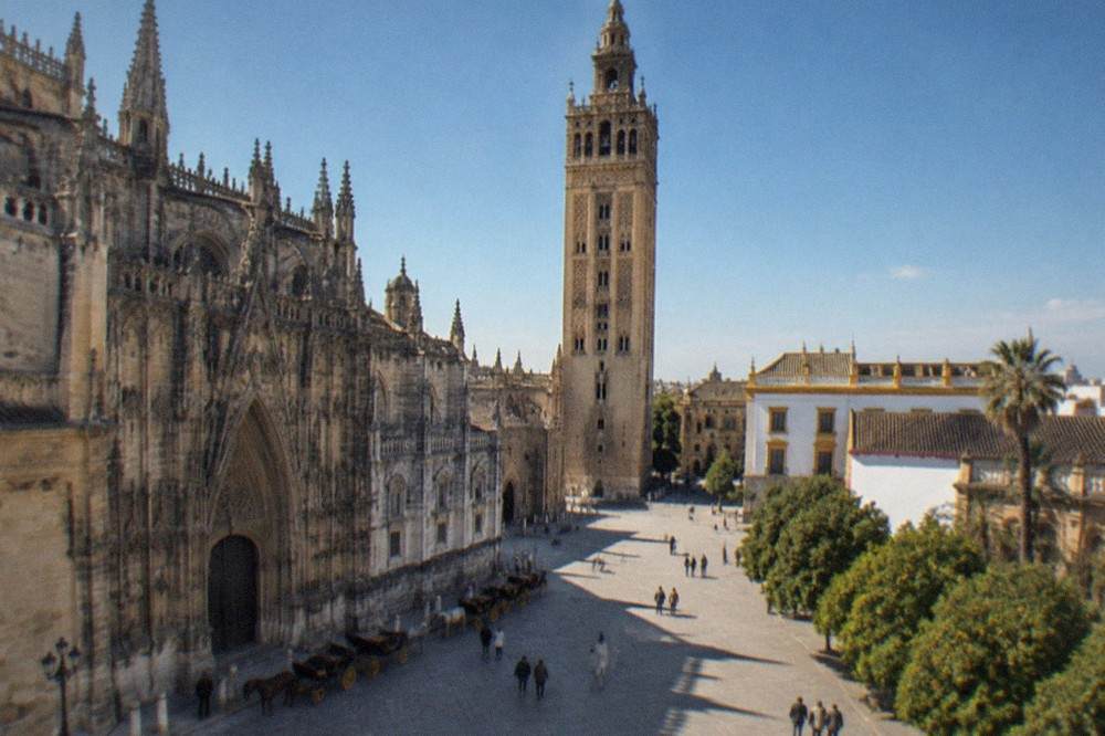 Horse-drawn carriages waiting beside the Gothic facade of Seville Cathedral