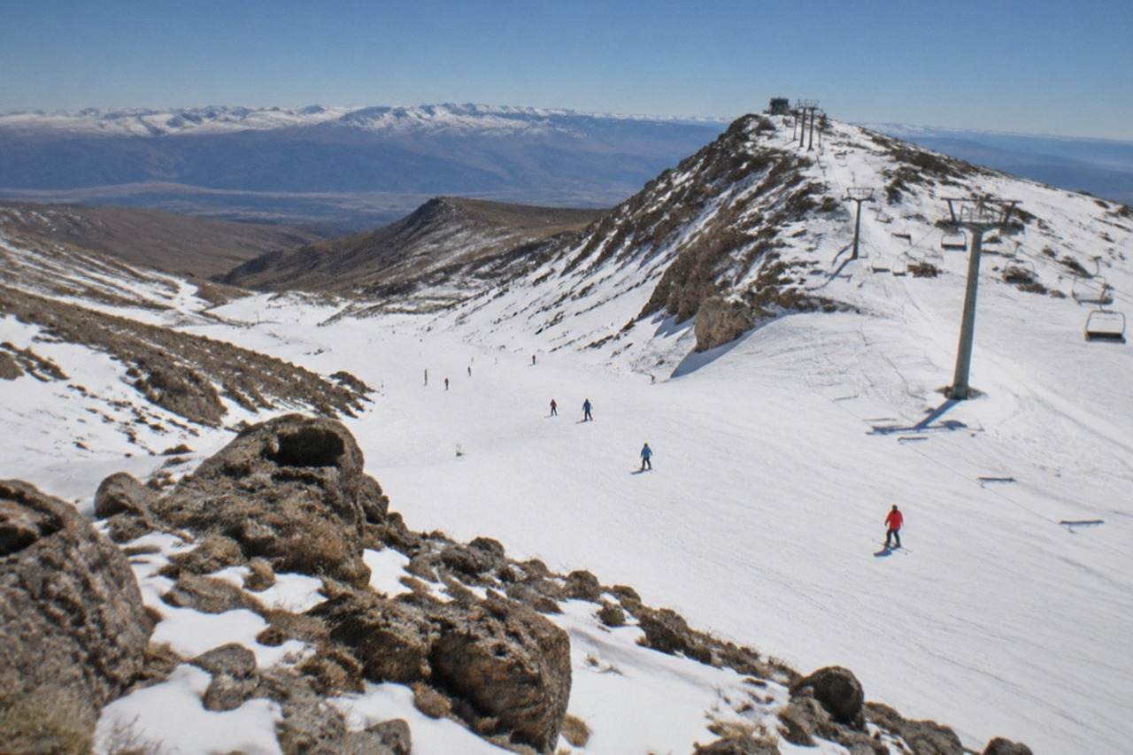 Rocky mountain trail above the tree line with distant peaks under a clear blue sky