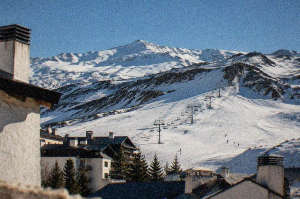View from a city rooftop toward a long line of mountains with snow on the highest ridges