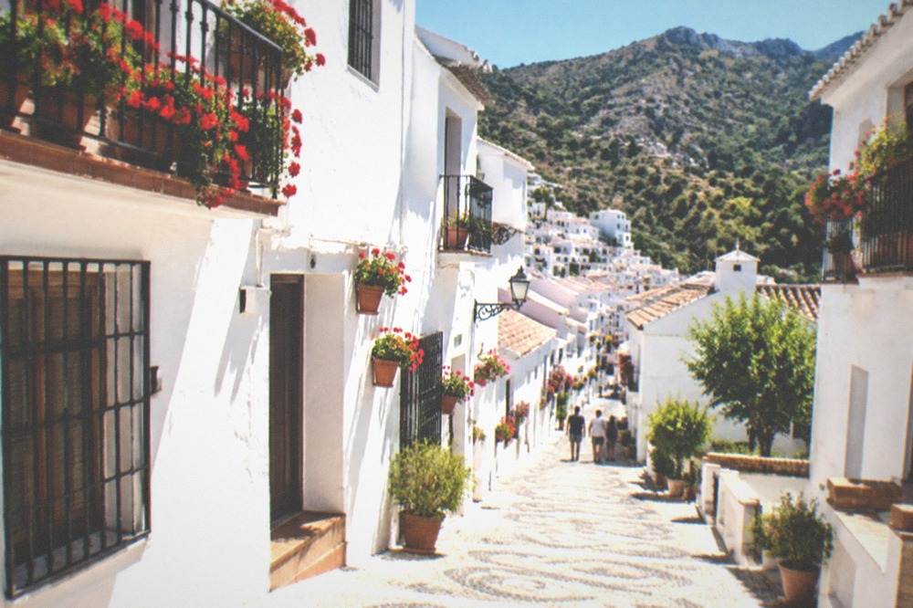 White village houses clinging to a green mountainside with terraced fields