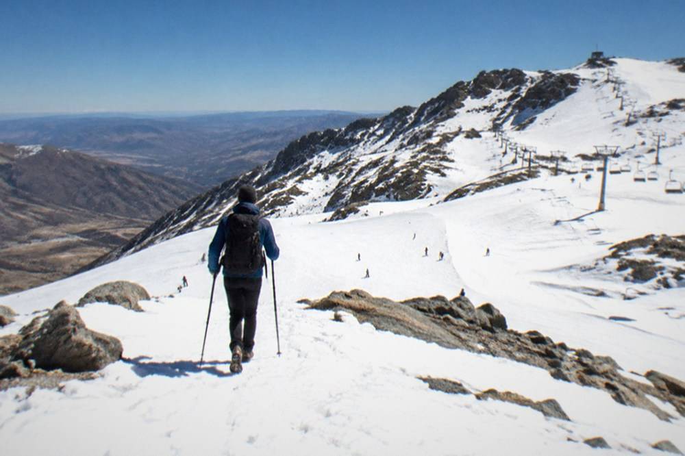 Hiker pausing on a high ridge with a wide panorama of valleys and distant ridgelines