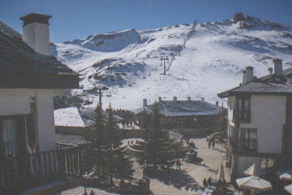 A sunny plaza in Granada with the snowy Sierra Nevada ridge visible in the distance