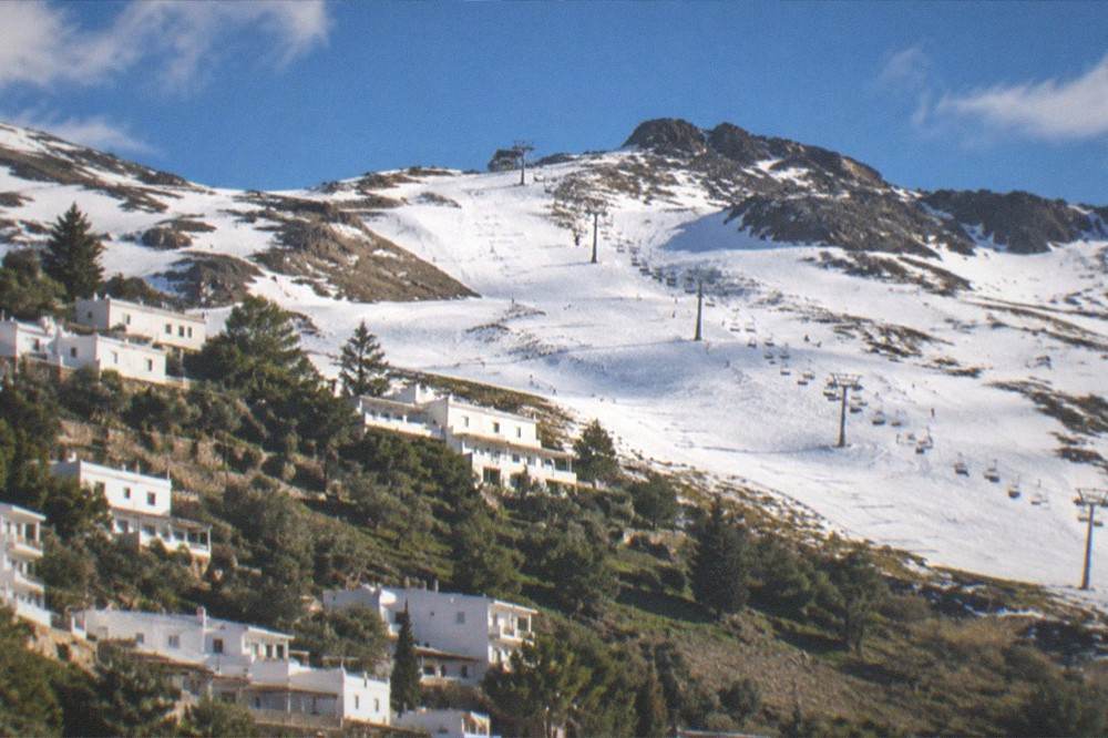 A white mountain village with flat roofs terraced on a green hillside