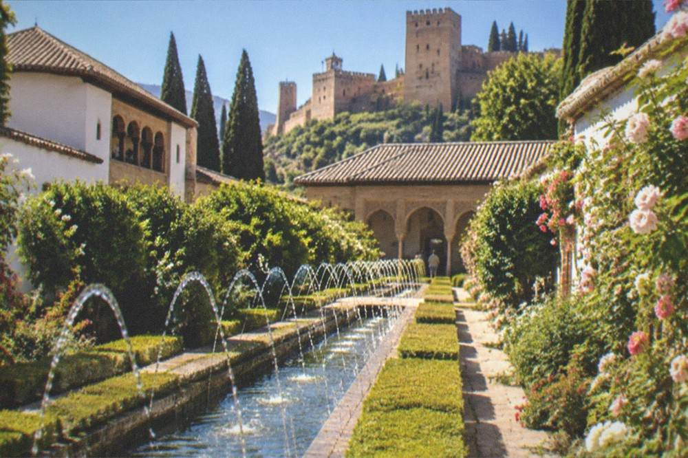 Water channels and clipped hedges in the Generalife gardens with the palace buildings behind