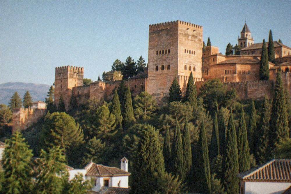 The Comares Tower of the Alhambra lit softly at dusk above the palace walls