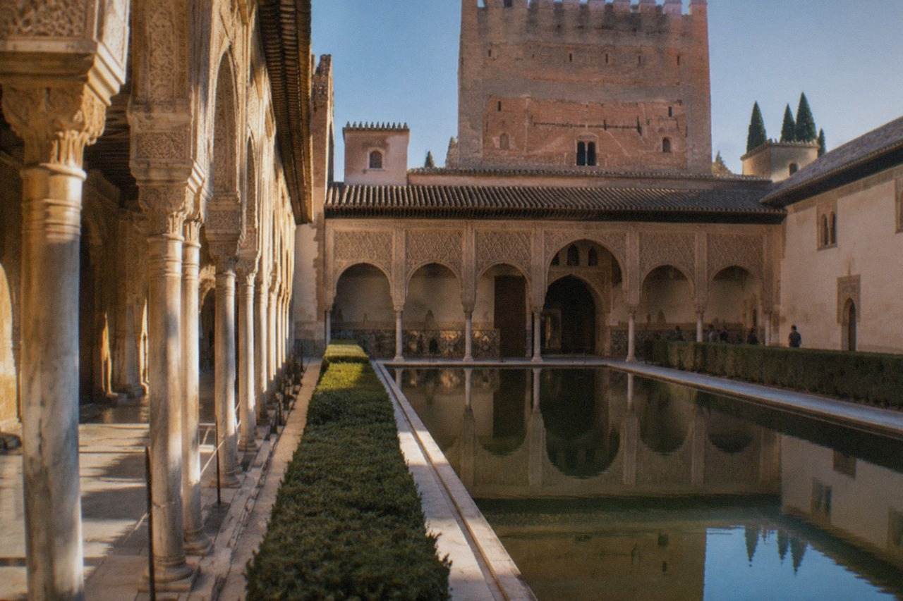 The Nasrid Palaces of the Alhambra with ornate arches and carved walls under a clear sky