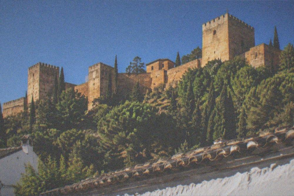 The Alhambra towers lit by warm floodlights against a dark blue evening sky