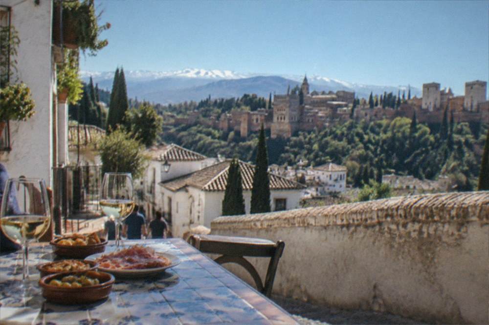 A tiled Granada bar top with small plates of tapas and glasses of wine