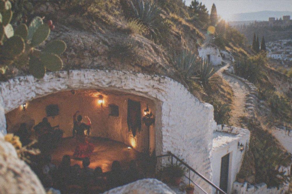 A flamenco dancer performing inside a whitewashed cave venue in Sacromonte under warm lights