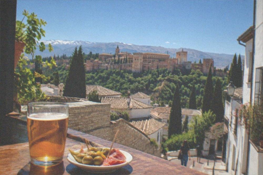 A small bar counter in Granada with a glass of beer and a complimentary plate of tapas beside it
