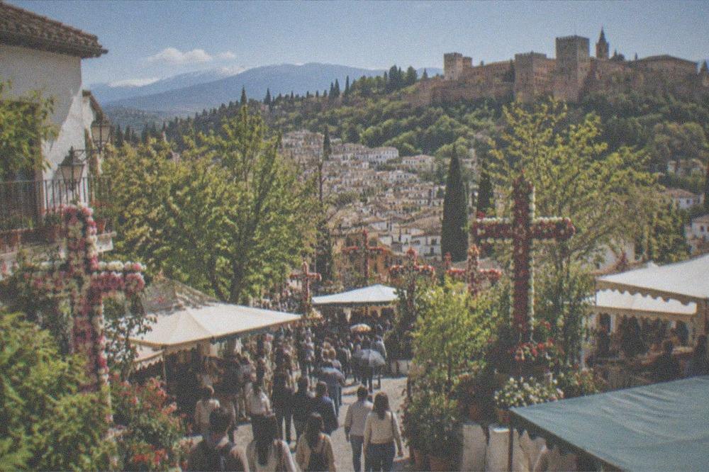 A festive street in Granada during a spring festival with decorated crosses and crowded food stalls