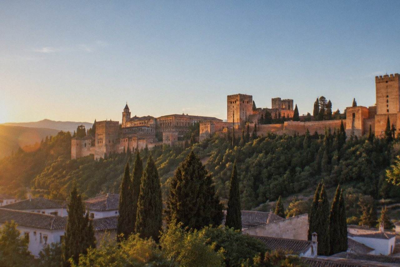The Alhambra palace complex seen across the city from a hillside viewpoint at golden hour