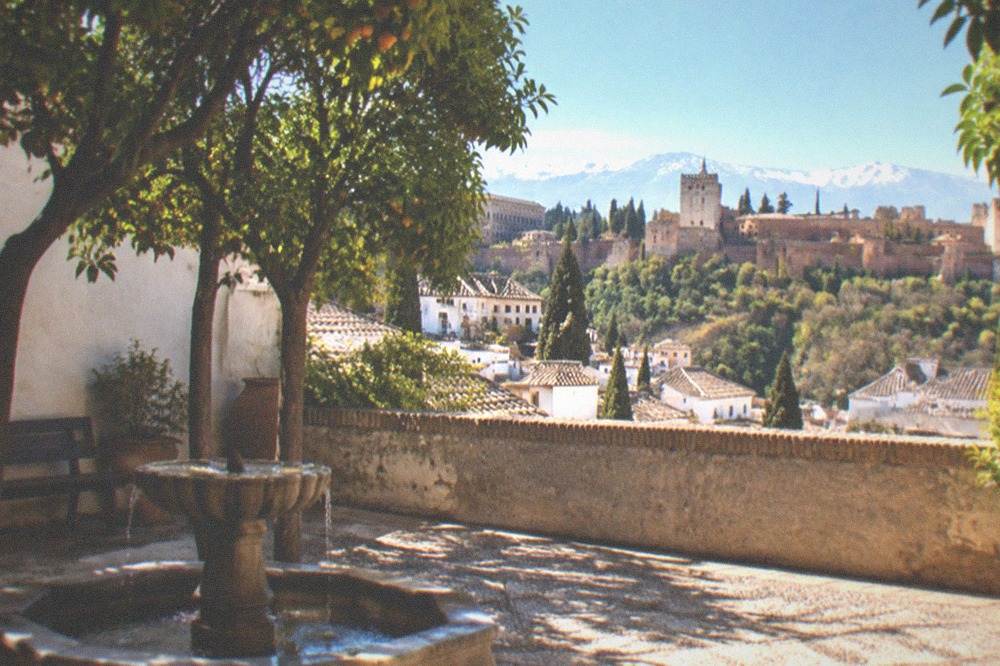 Shaded patio with orange trees and a stone fountain in the Granada afternoon