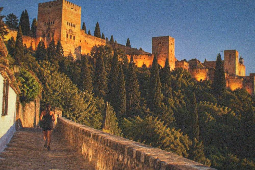 The Alhambra towers glowing under evening floodlights against a dark blue sky