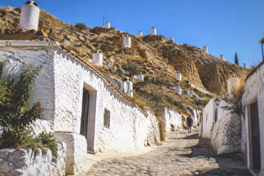 A narrow cobbled lane climbing between white cave houses on the Sacromonte hillside