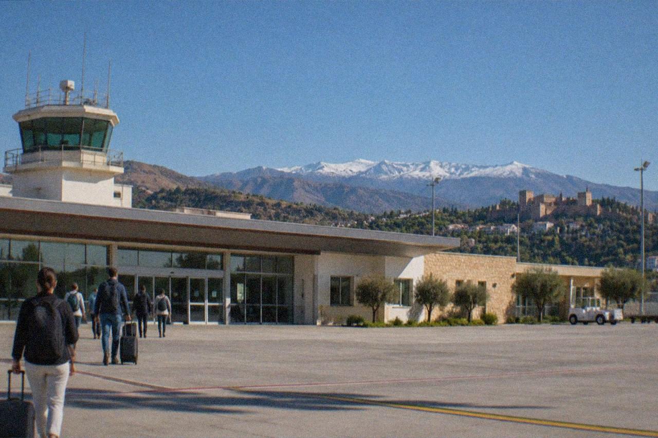 A small regional airport terminal building under a clear blue Andalusian sky with hills in the background