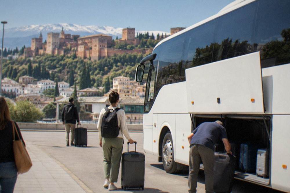 A white intercity coach parked at an airport curb with passengers loading luggage into the hold