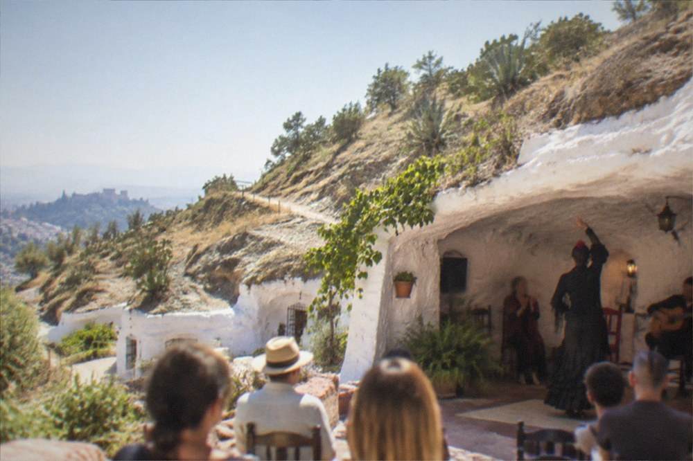 A flamenco performance inside a whitewashed cave venue in Sacromonte with a guitarist and dancers