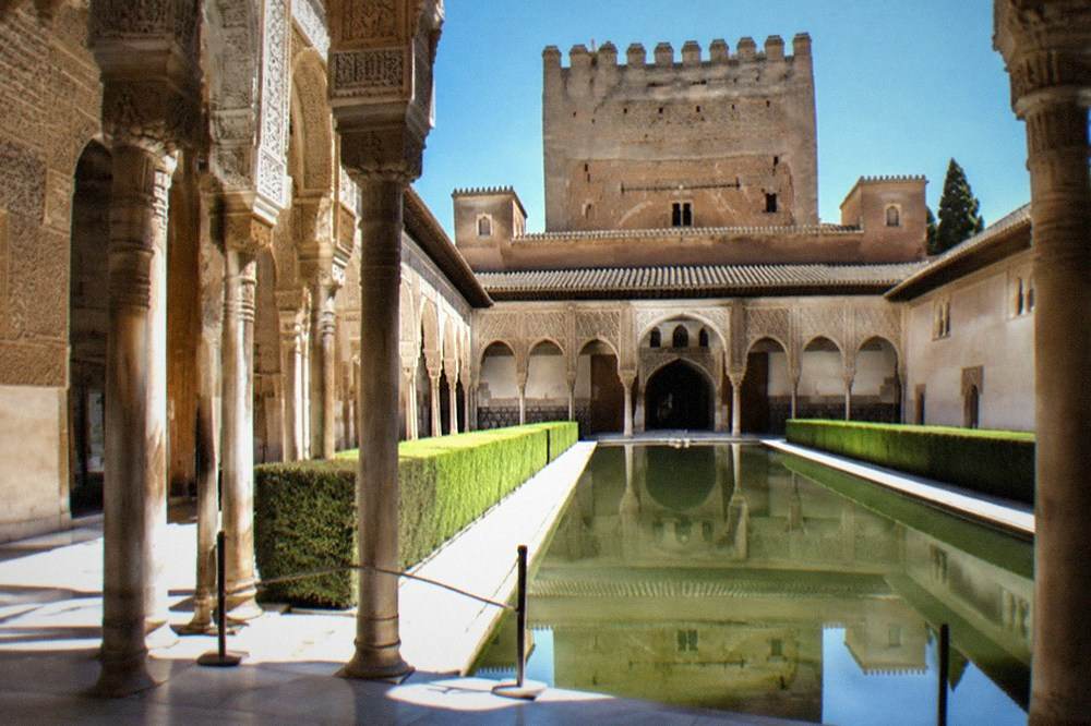 The intricate carved stucco walls of the Nasrid Palaces lit by daylight through latticed windows