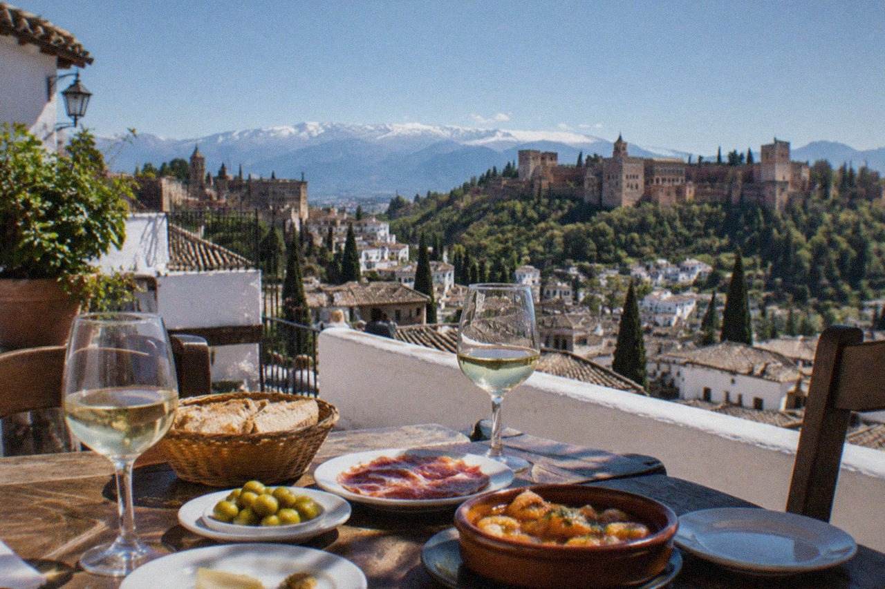 A table in a Granada tapas bar set with small plates, bread and glasses of wine